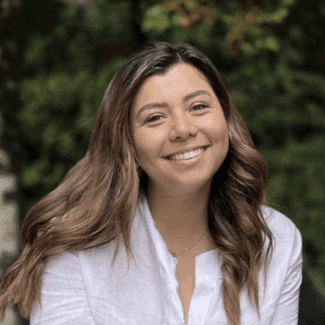 Yireth Villaverde smiling at the camera against a background of trees.